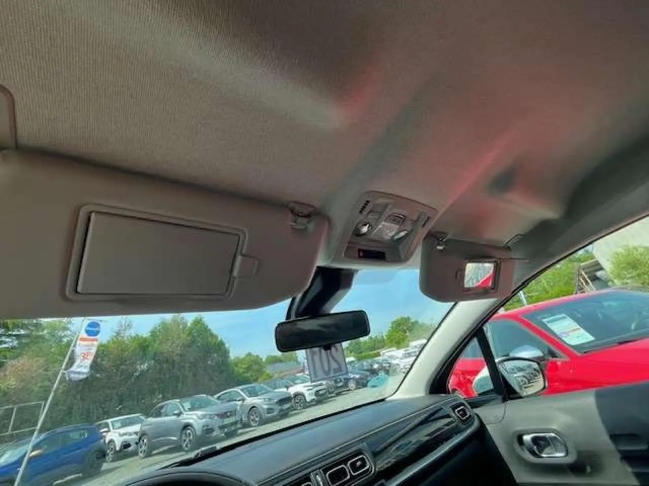 Vue intérieure avant de la Citroën C3 2023 noire métal, montrant tableau de bord et pare-soleil ouverts.