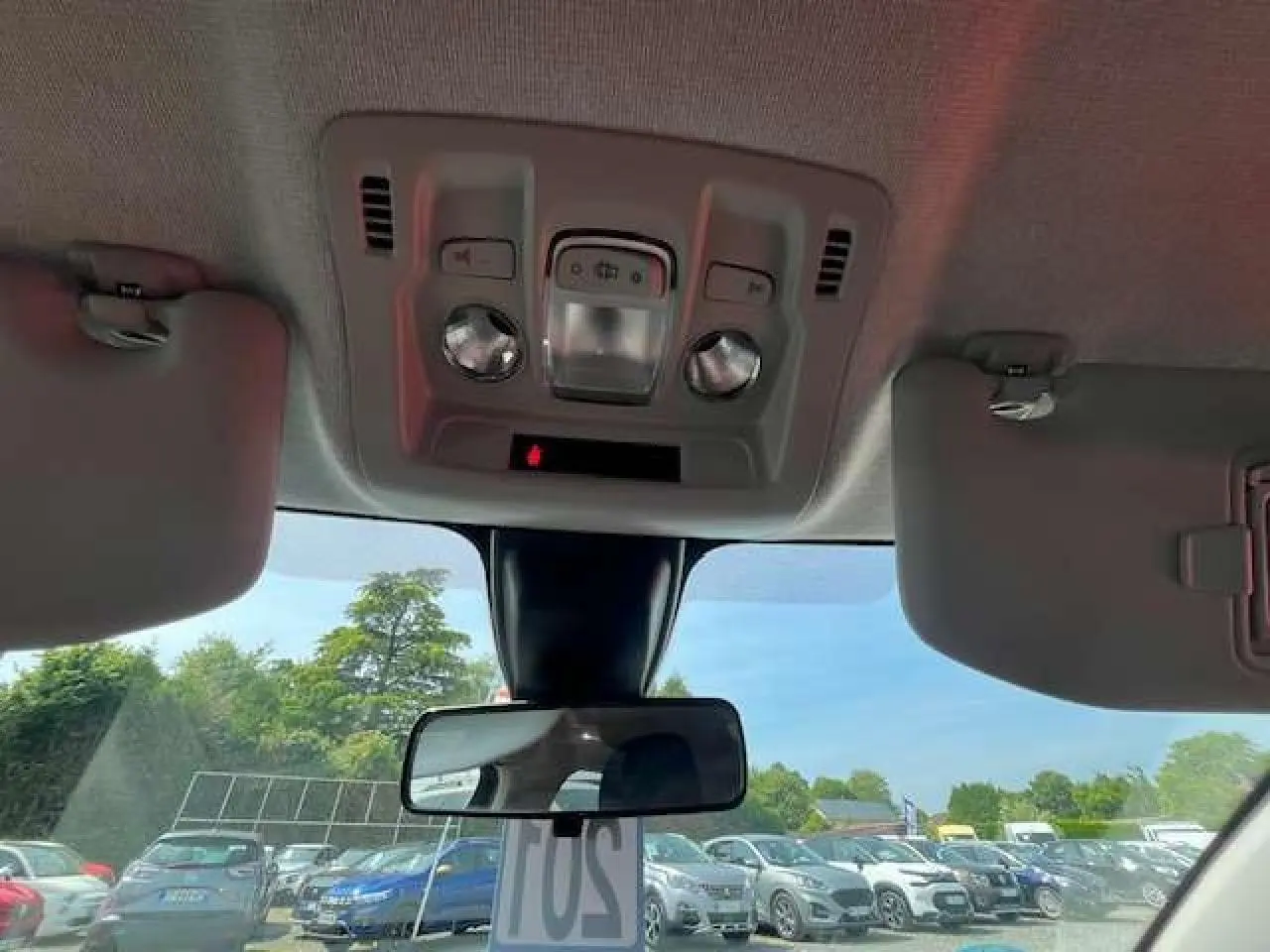 Vue intérieure du plafond et rétroviseur central d'une Citroën C3 noire métal 2023, avec pare-soleil baissé.