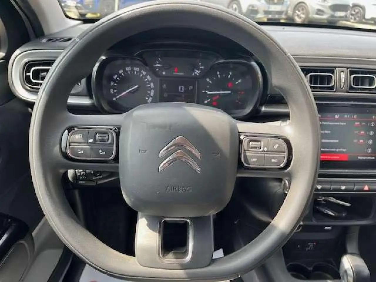 Vue centrée sur le volant noir de la Citroën C3 2023 avec tableau de bord et écran tactile en arrière-plan.