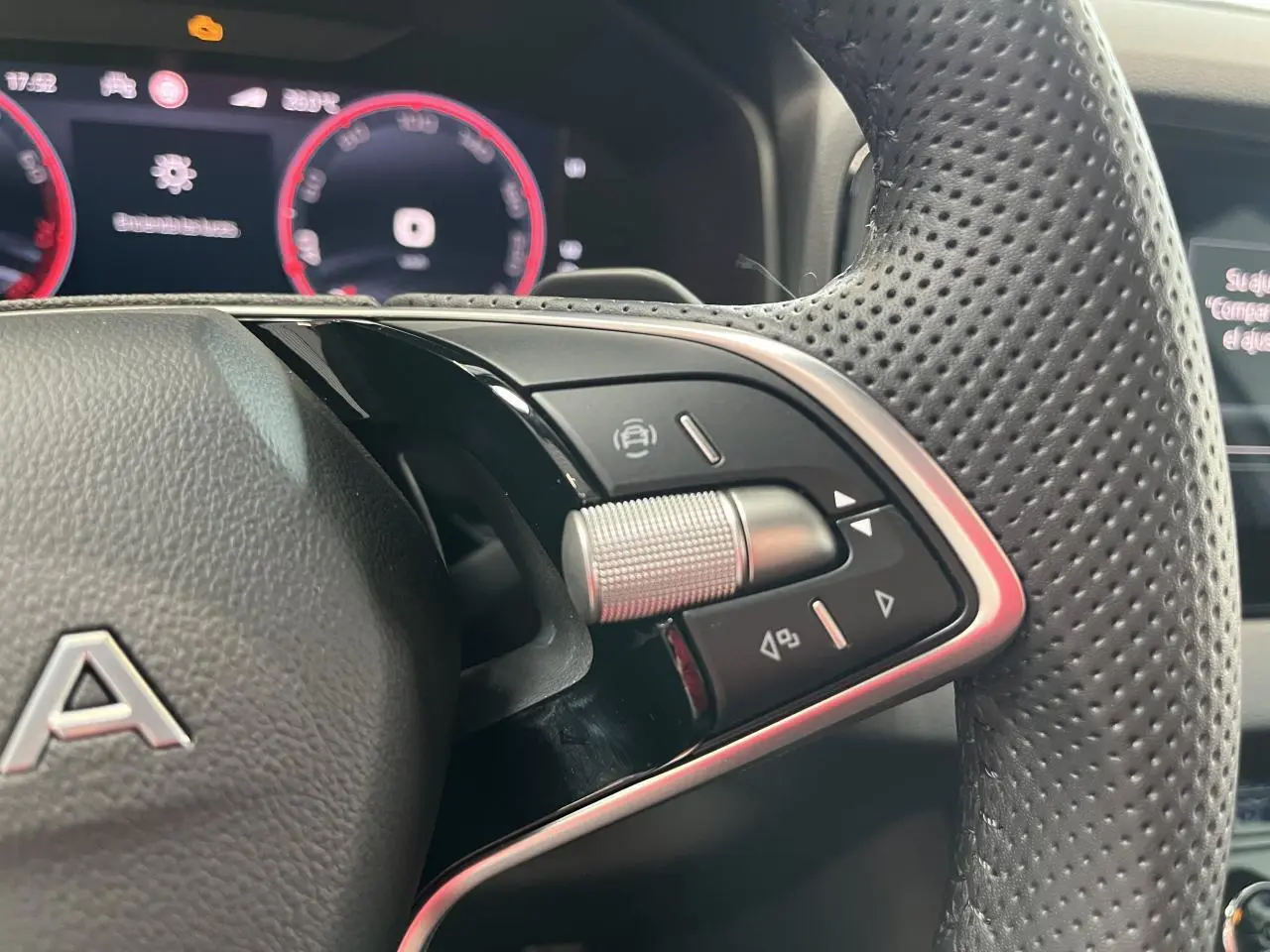 Gros plan sur le volant perforé noir du Skoda Karoq 2025 avec commandes multifonctions et tableau de bord digital rouge.