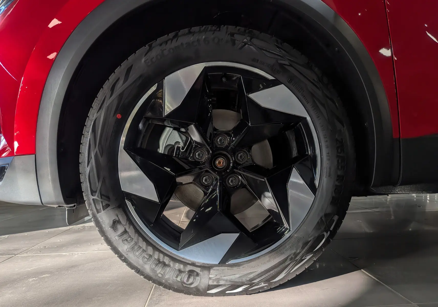 Gros plan sur la roue avant gauche du Renault Captur E-TECH 2025 rouge Flamme avec jante noire et argentée design géométrique.