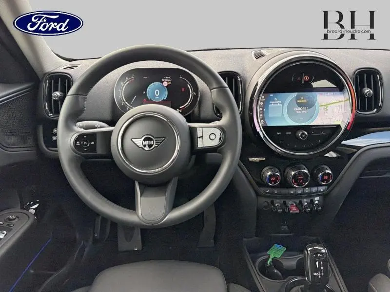 Vue intérieure du tableau de bord et volant noir du MINI Countryman 2023 avec écran tactile rond et commandes digitales.