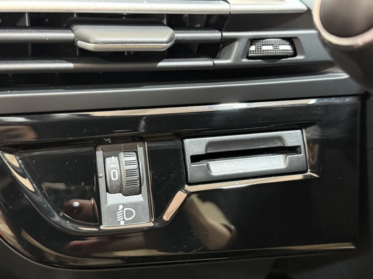 Gros plan sur la commande de réglage des phares et la fente de carte dans l’habitacle noir du Citroën C4 Spacetourer 2020.