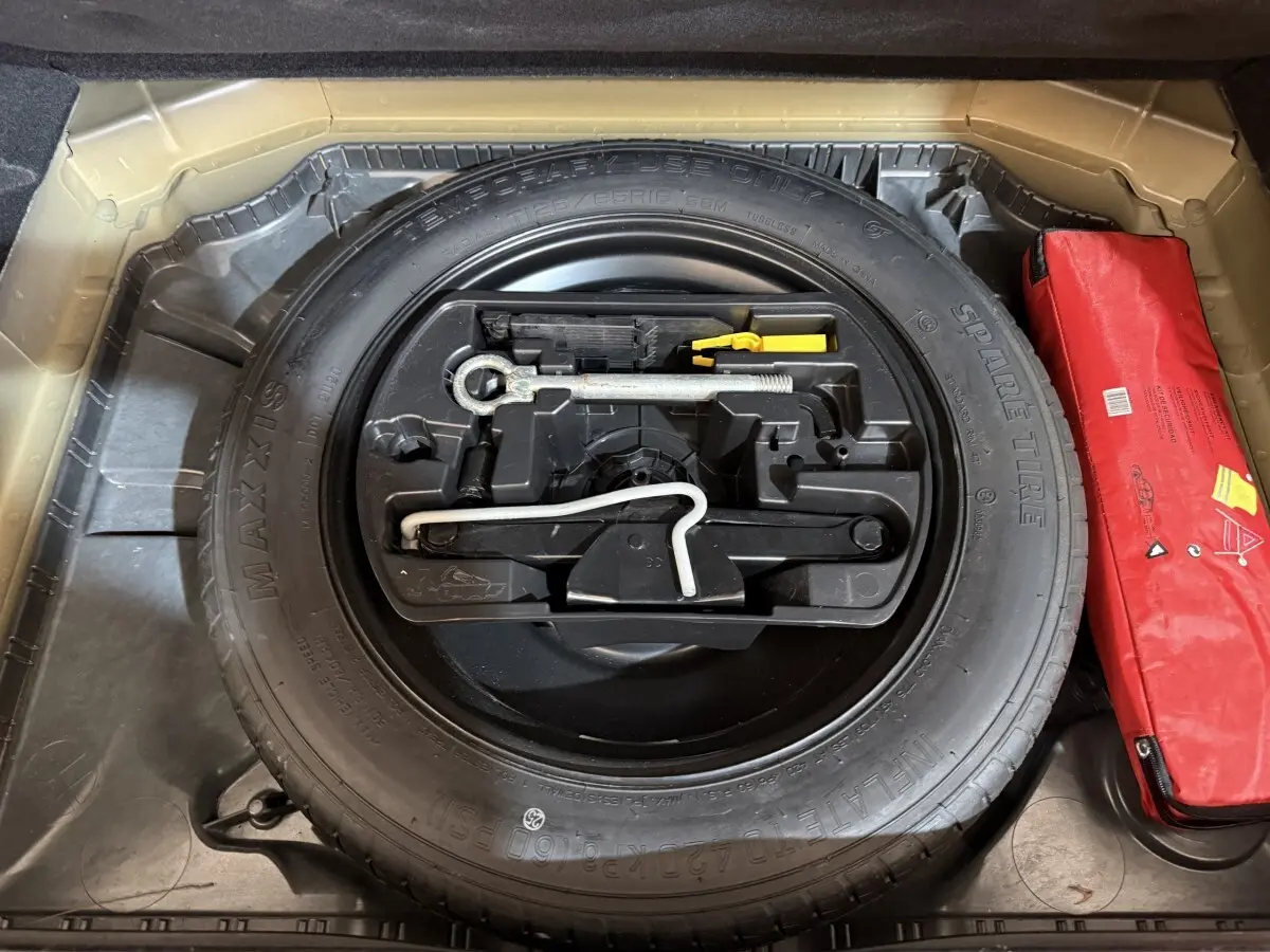 Vue rapprochée de la roue de secours noire et des outils de bord dans le coffre d'une Citroën C4 Spacetourer noire.