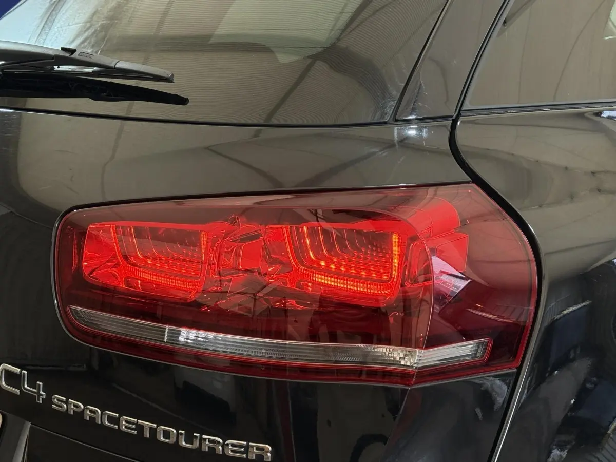 Gros plan sur le feu arrière droit rouge et le logo C4 Spacetourer sur la carrosserie noire brillante.