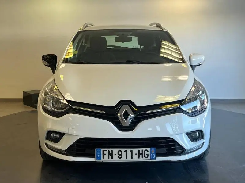 Vue frontale d'une Renault Clio Estate blanche Glacier avec calandre noire et phares halogènes allumés.