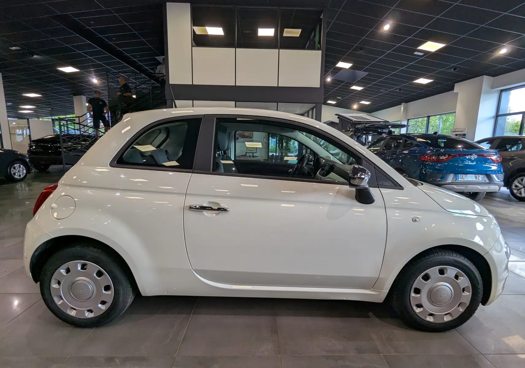Profil côté droit de la Fiat 500 1.2 69 CH Popstar blanche Bossanova, compacte et élégante en showroom.