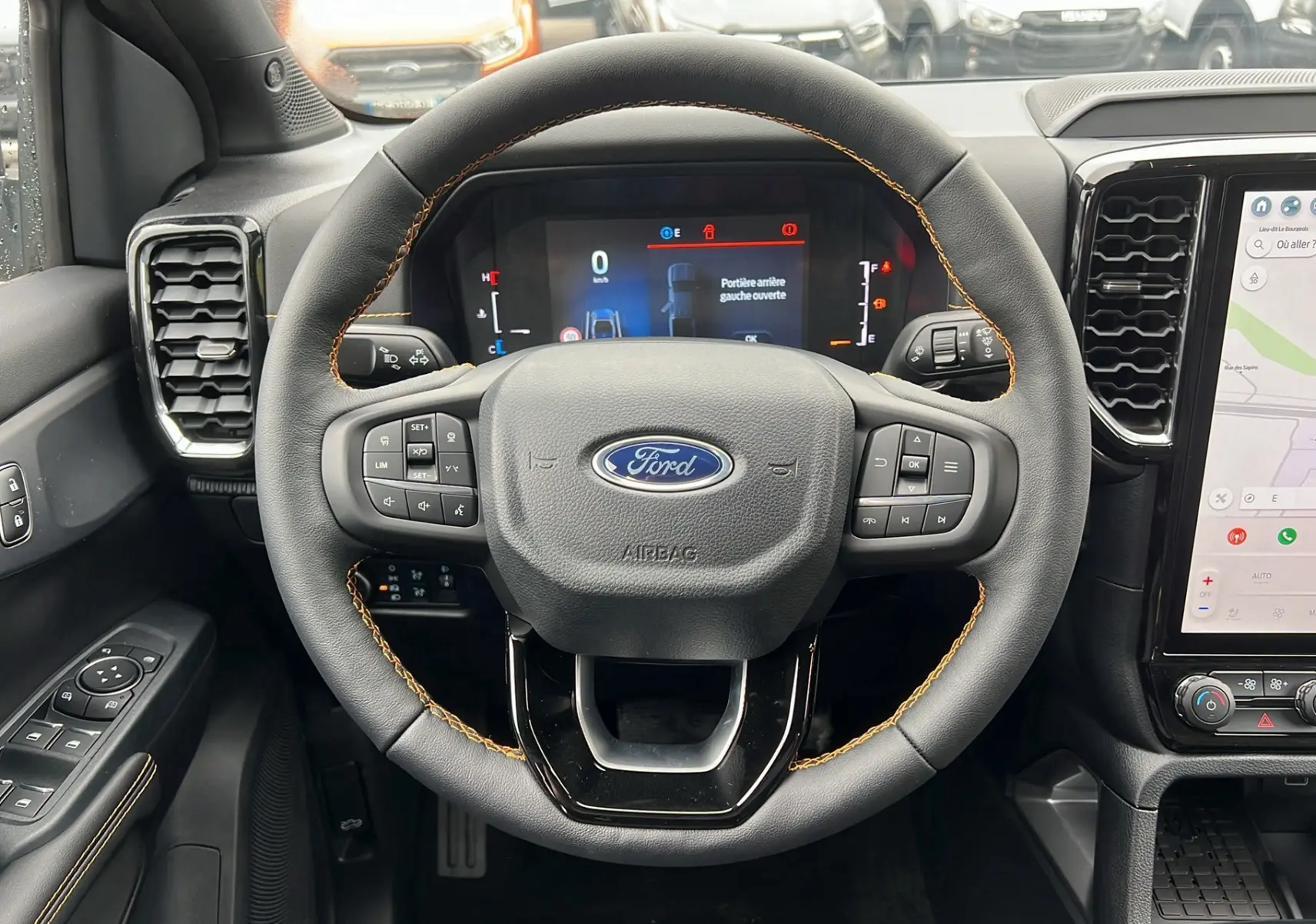 Vue intérieure centrée sur le volant du Ford Ranger 3.0 V6 gris carbone avec tableau de bord numérique et écran tactile.