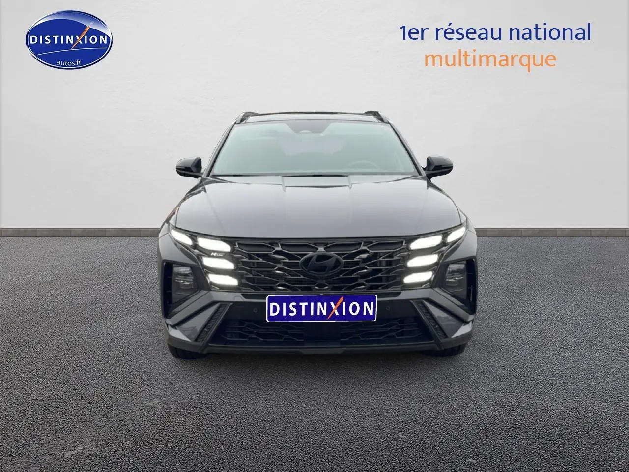 Vue frontale du Hyundai Tucson gris écotronique avec calandre n-line et feux LED allumés sur fond neutre.