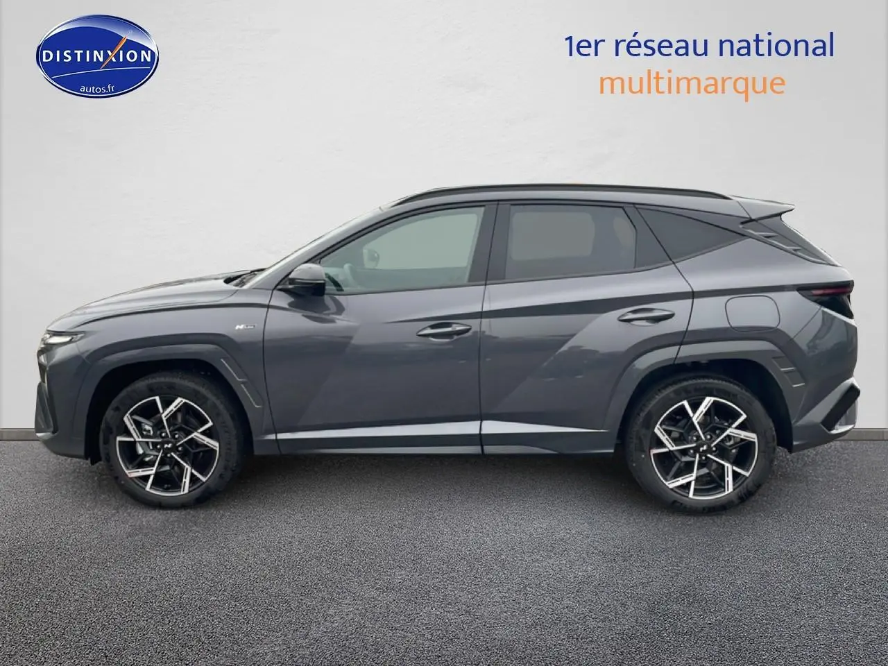 Vue de profil côté gauche du Hyundai Tucson 2025 gris écotronique avec jantes alliage 19 pouces et lignes anguleuses marquées.