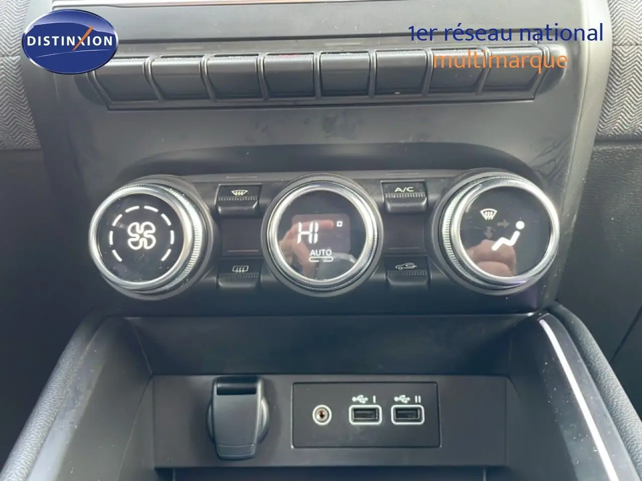 Gros plan sur la console centrale de la Renault Clio rouge Désir Métal, montrant les commandes de climatisation et ports USB.