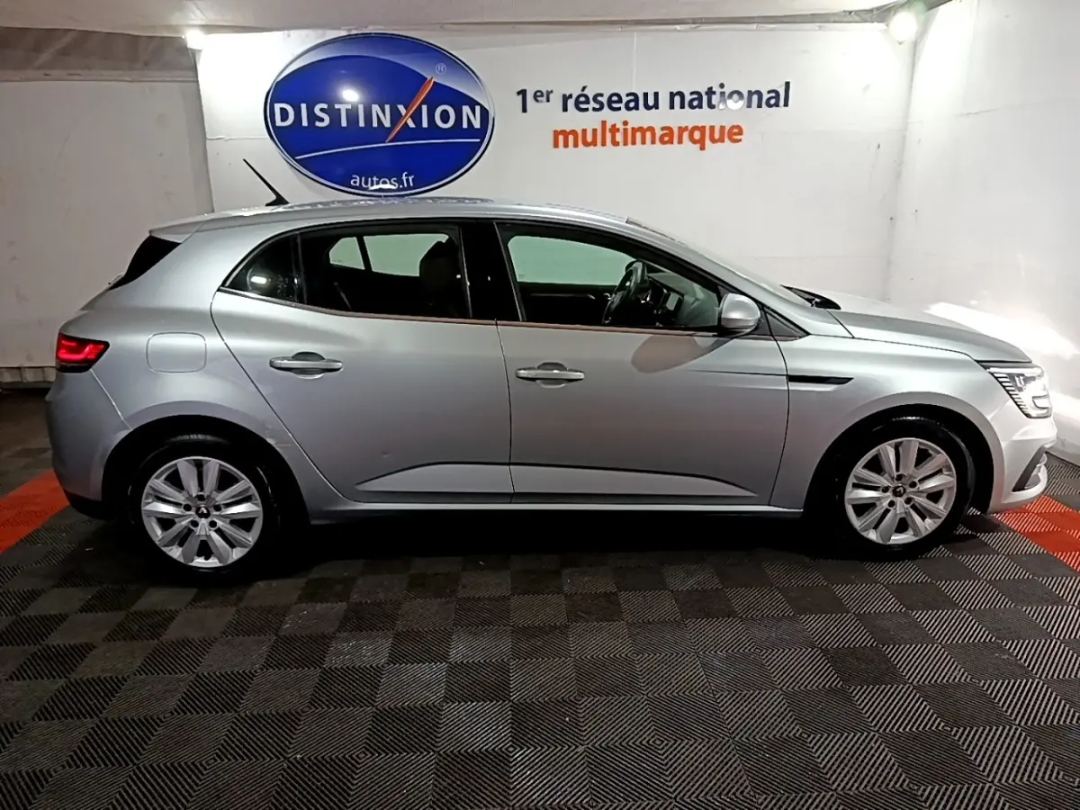 Profil droit d'une Renault Mégane Business Blue dCi 115 EDC gris clair, stationnée en intérieur sur sol damier.