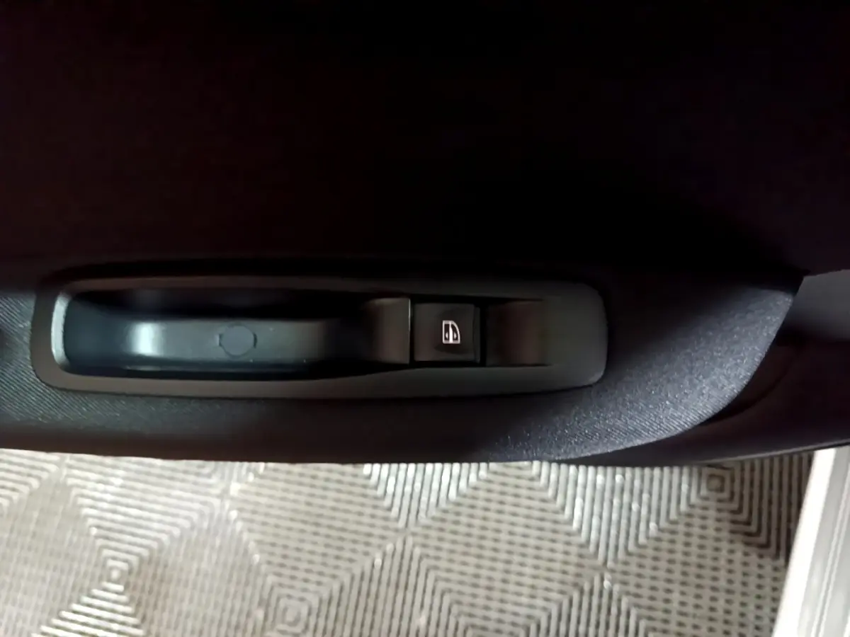 Gros plan sur la commande de lève-vitre noir intégrée à la porte intérieure d’une Renault Mégane Business Blue dCi 115 EDC gris clair.