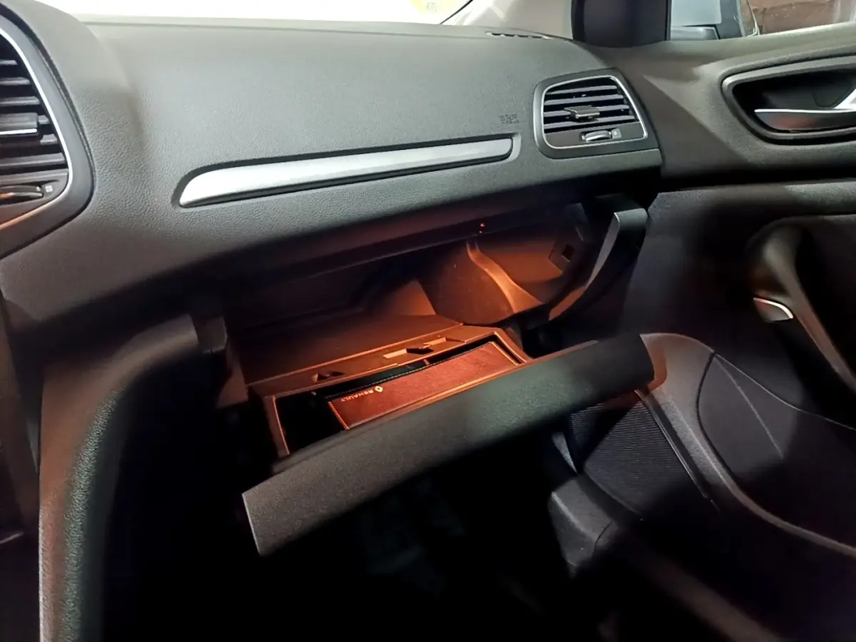 Intérieur Renault Mégane Business Blue dCi 115 2021, vue sur boîte à gants ouverte côté passager avec éclairage orange.