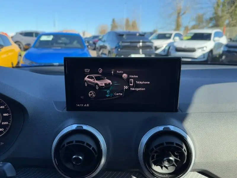 Écran central du tableau de bord de l'Audi Q2 30 TDI 2024 affichant le menu navigation, vue intérieure avant.