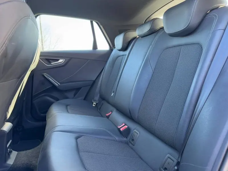 Vue latérale droite de la banquette arrière en cuir noir de l'Audi Q2 30 TDI S line 2024, avec appuie-têtes intégrés.