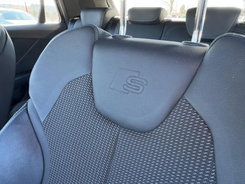 Gros plan sur le siège avant noir du Audi Q2 30 TDI S line 2024 avec logo S embossé sur l'appuie-tête.