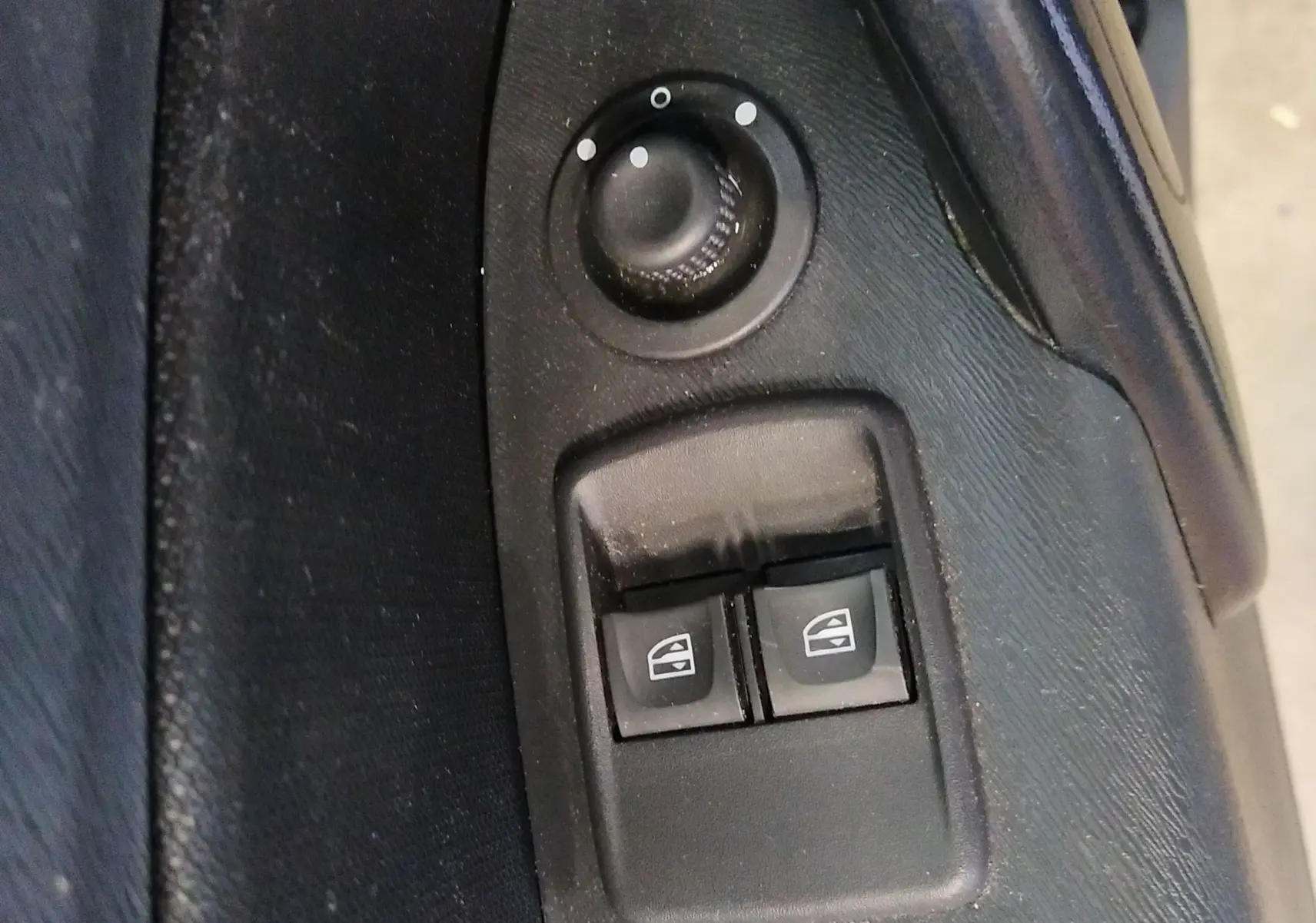 Gros plan sur les commandes de réglage des rétroviseurs et des vitres électriques côté conducteur du Renault Kangoo blanc 2019.