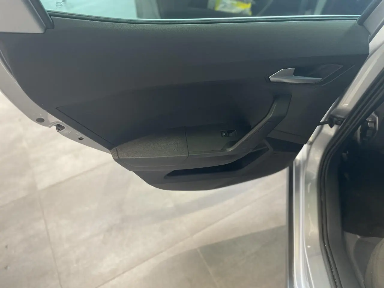Vue rapprochée de la porte avant droite noire d'un SEAT Arona 2024 couleur GRS, avec poignée et commande de vitre.