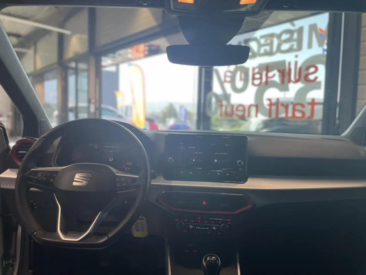 Intérieur du SEAT Arona 2024 vu de face, volant sport cuir noir et écran tactile central lumineux.