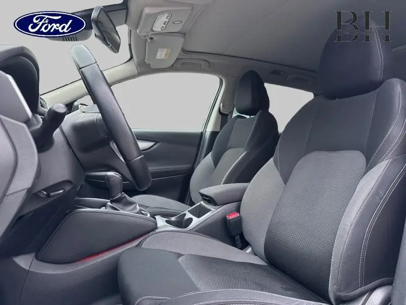 Vue intérieure côté conducteur du Nissan Qashqai 1.6 dCi 130ch gris Squale, sièges sport en tissu noir avec accoudoirs centraux.
