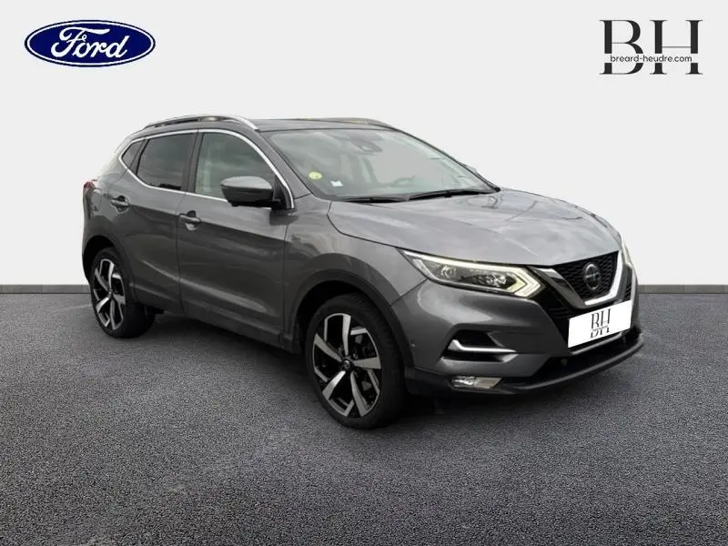 Nissan Qashqai gris Squale vu en 3/4 avant droit avec jantes alliage et barres de toit visibles