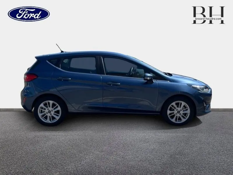 Profil droit d'une Ford Fiesta 2022 bleu azur métallisé avec jantes alu et poignées ton carrosserie visibles.