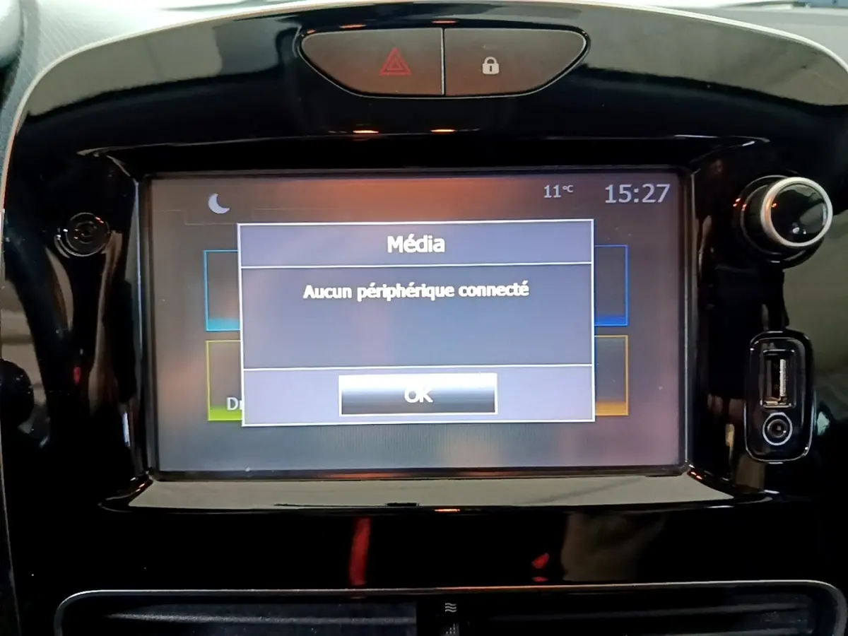 Vue rapprochée de l’écran tactile central noir brillant de la Renault Clio Business gris clair affichant un message média.