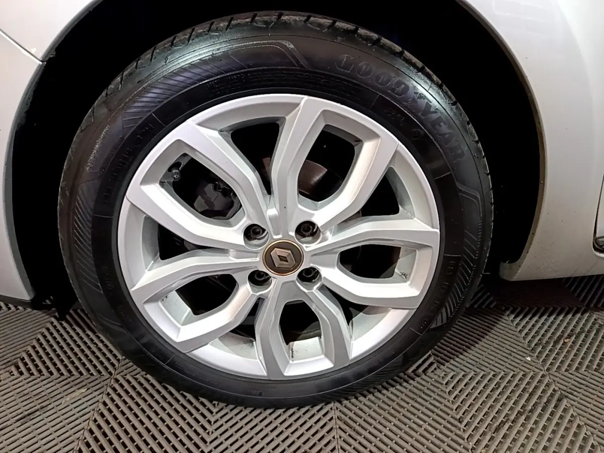 Gros plan sur la roue avant droite d’une Renault Clio Business gris clair avec jante alliage à motif moderne.