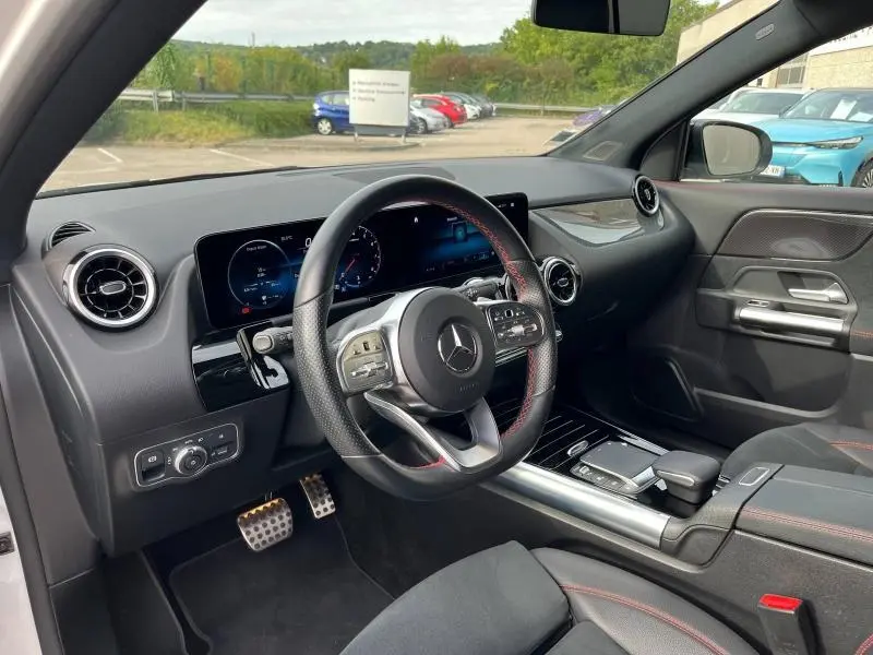 Intérieur côté conducteur du Mercedes GLA 200 AMG Line 2022, volant cuir noir avec surpiqûres rouges et tableau de bord digital.