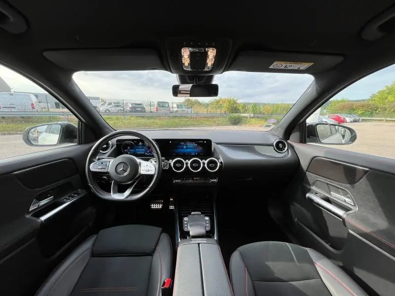 Intérieur noir du Mercedes GLA 200 AMG Line 2022, vue avant sur tableau de bord et volant cuir multifonction.