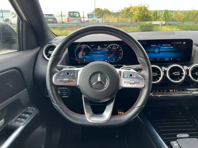 Vue centrée sur le volant sport cuir Nappa et tableau de bord numérique du Mercedes GLA 200 AMG Line blanc polaire 2022.