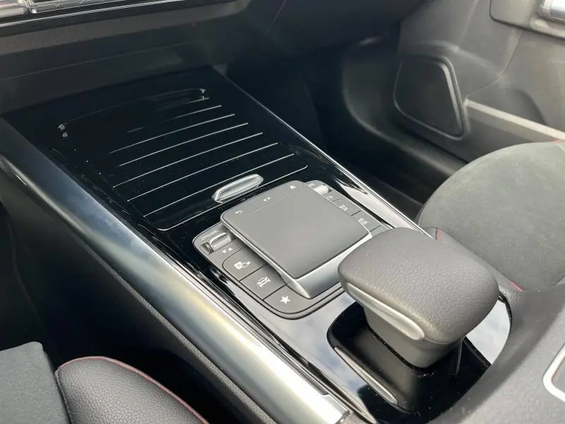 Vue rapprochée de la console centrale noire brillante du Mercedes GLA 200 AMG Line 2022 avec pavé tactile et accoudoir cuir.