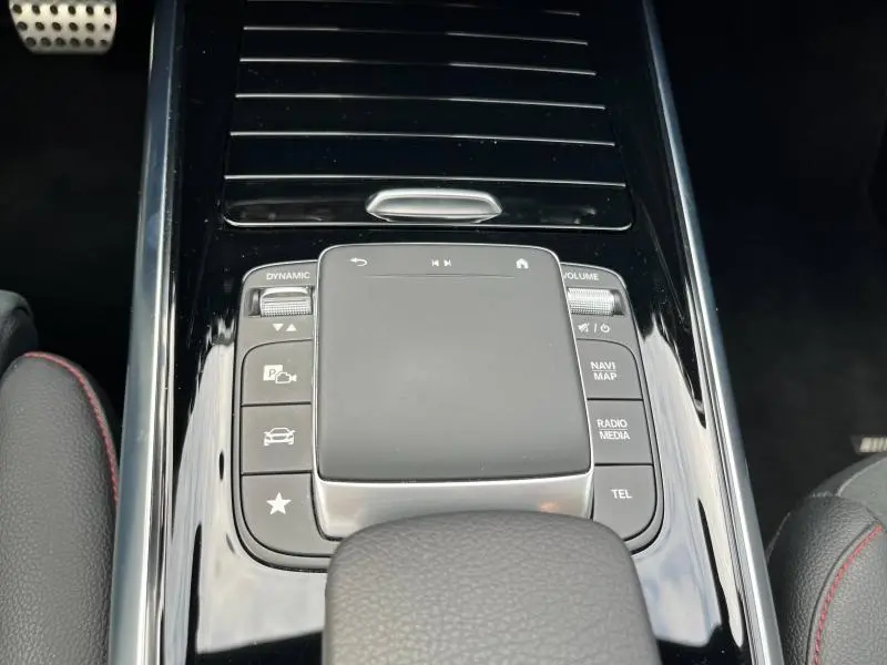 Gros plan sur la console centrale noire brillante du Mercedes GLA 200 AMG Line avec pavé tactile et commandes intégrées.