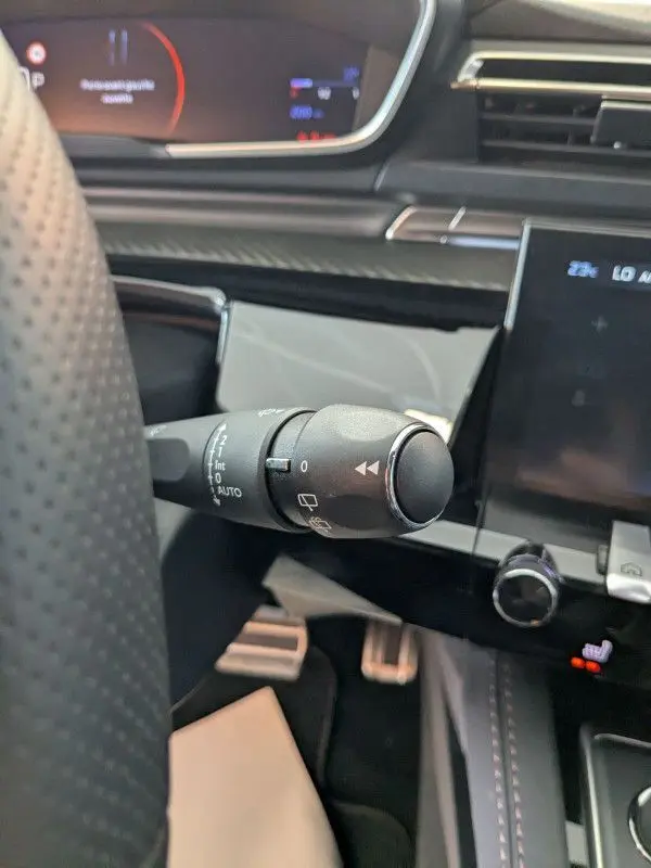 Gros plan sur la commande d'essuie-glace à gauche du volant dans l'habitacle gris noir du Peugeot 508 SW 2024.