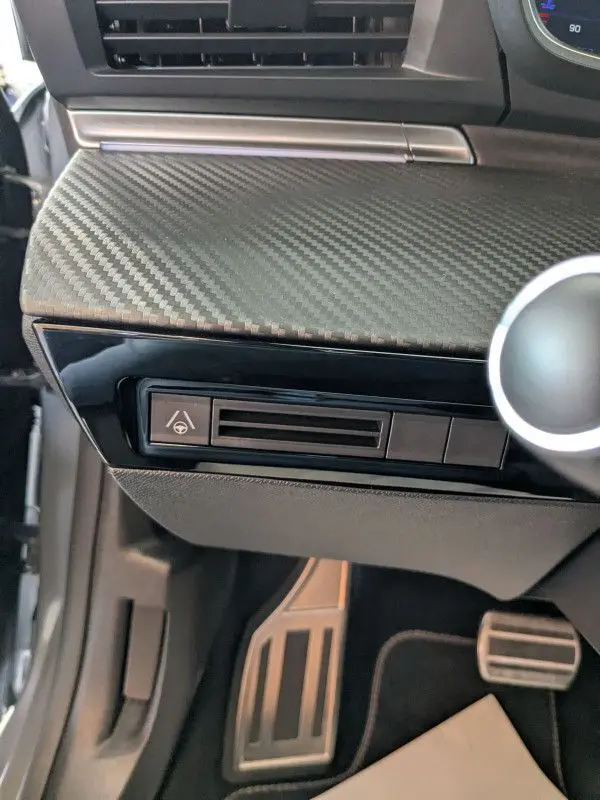 Détail du tableau de bord côté conducteur du Peugeot 508 SW gris Selenium 2024 avec texture carbone et commande d'aide à la conduite.