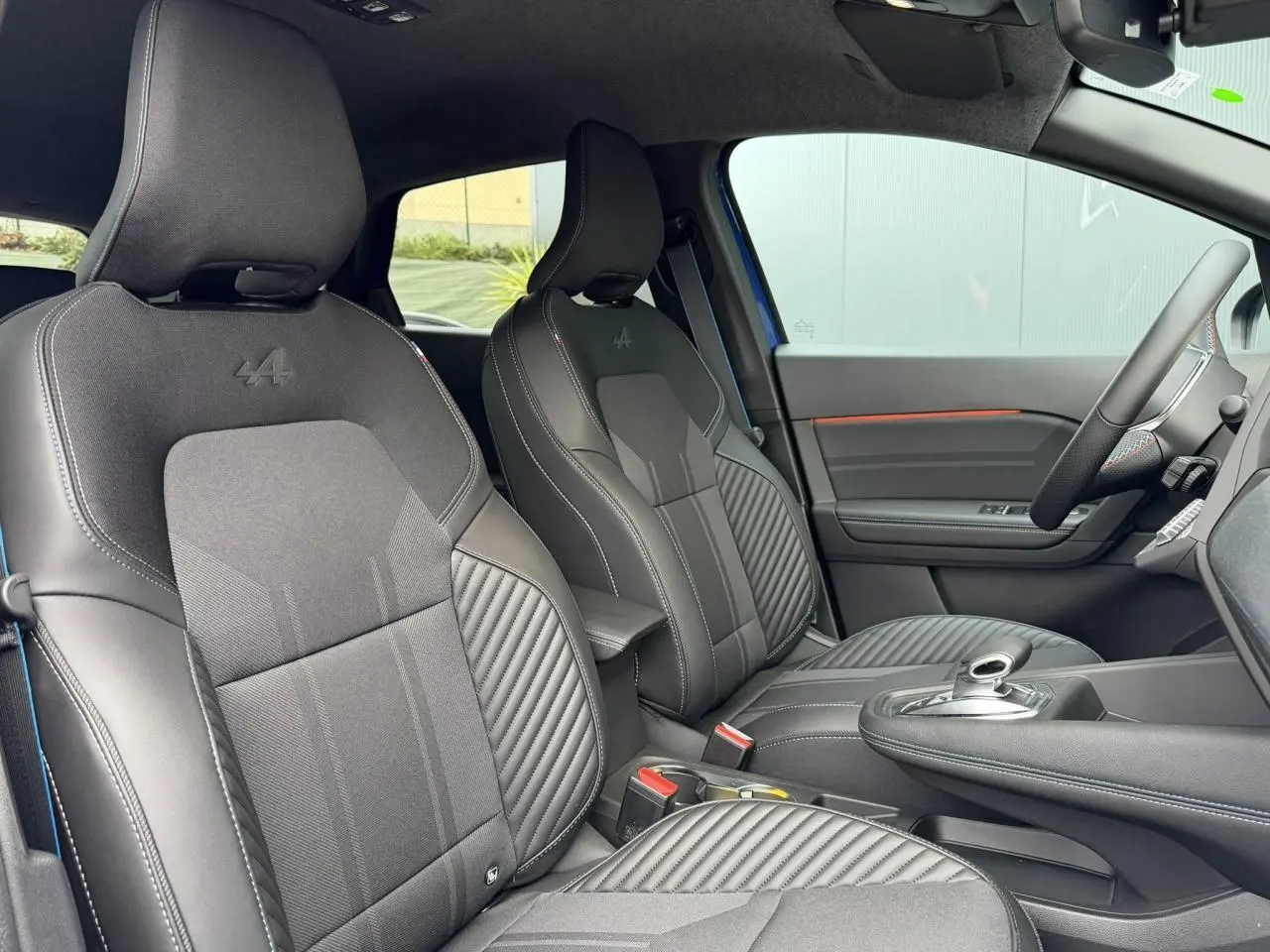 Vue intérieure côté droit du Renault Captur Esprit Alpine 2025, sièges tissu noir avec logo Alpine brodé.