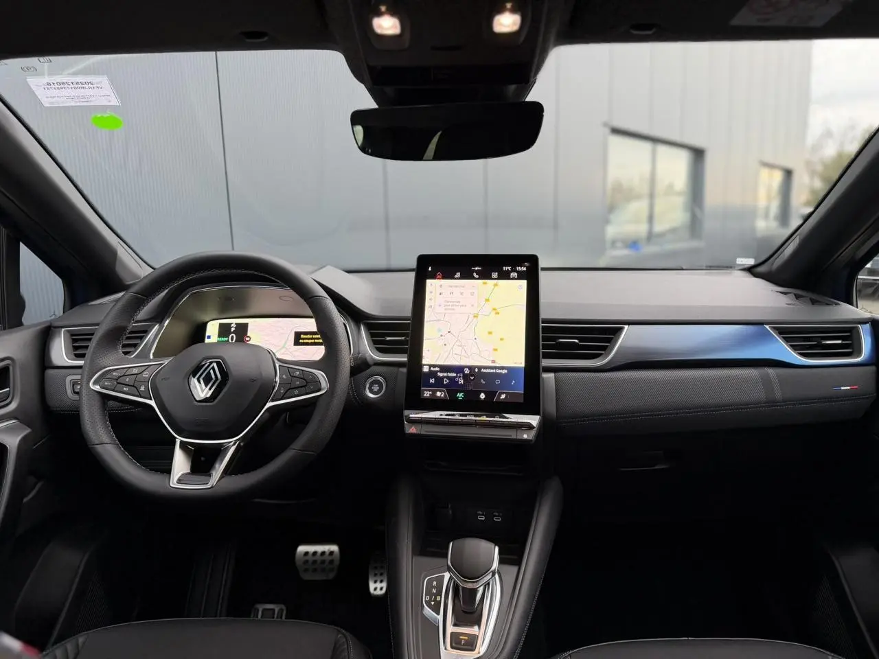 Vue intérieure frontale du tableau de bord du Renault Captur Bleu Iron avec écran tactile vertical et volant multifonction.