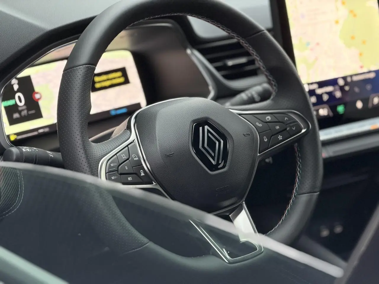 Vue rapprochée du volant noir avec surpiqûres tricolores du Renault Captur 2025, tableau de bord numérique en arrière-plan.