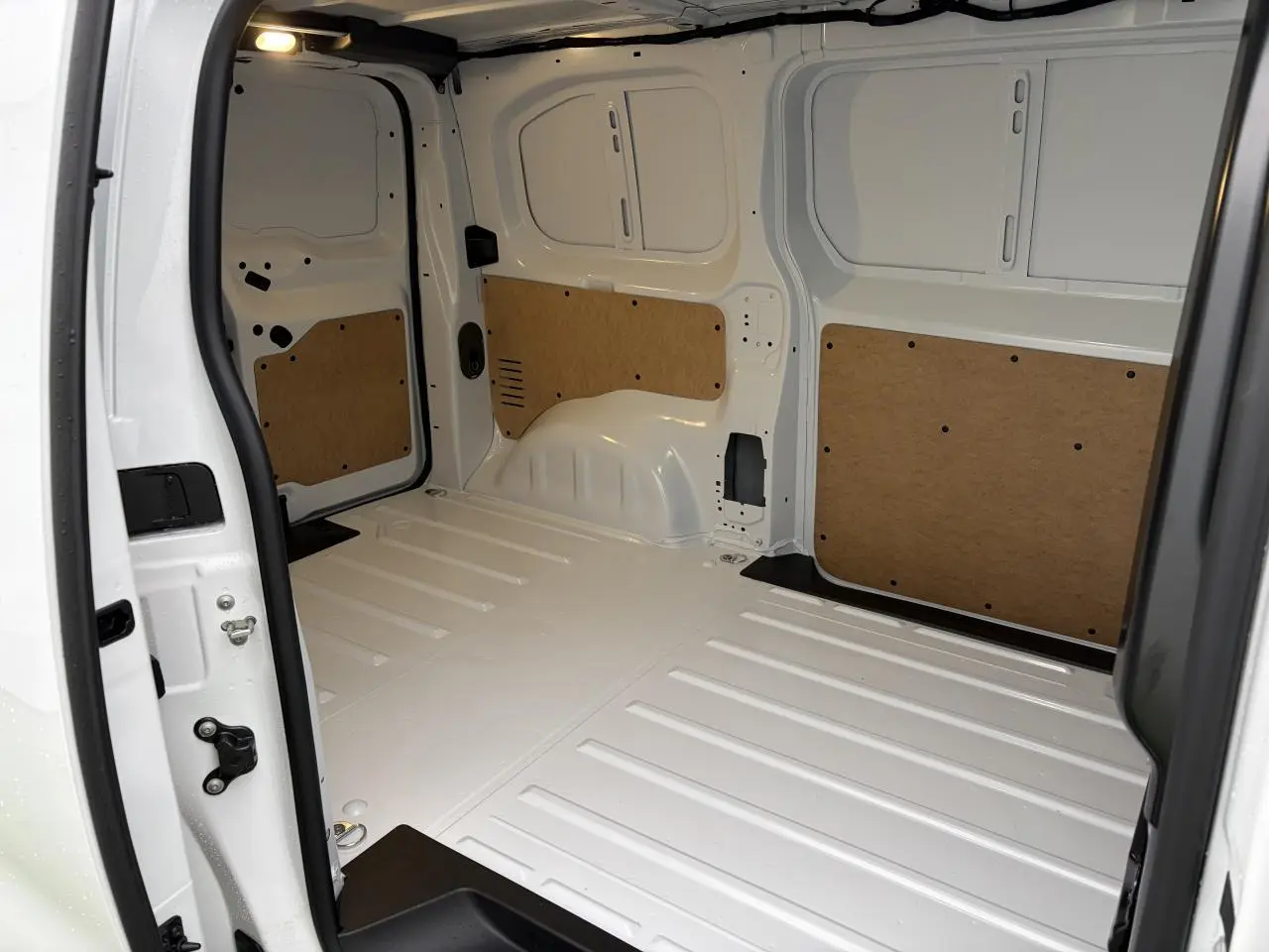Vue intérieure arrière du fourgon Peugeot Expert blanc Icy, montrant l'espace de chargement avec éclairage LED et panneaux de protection en bois.