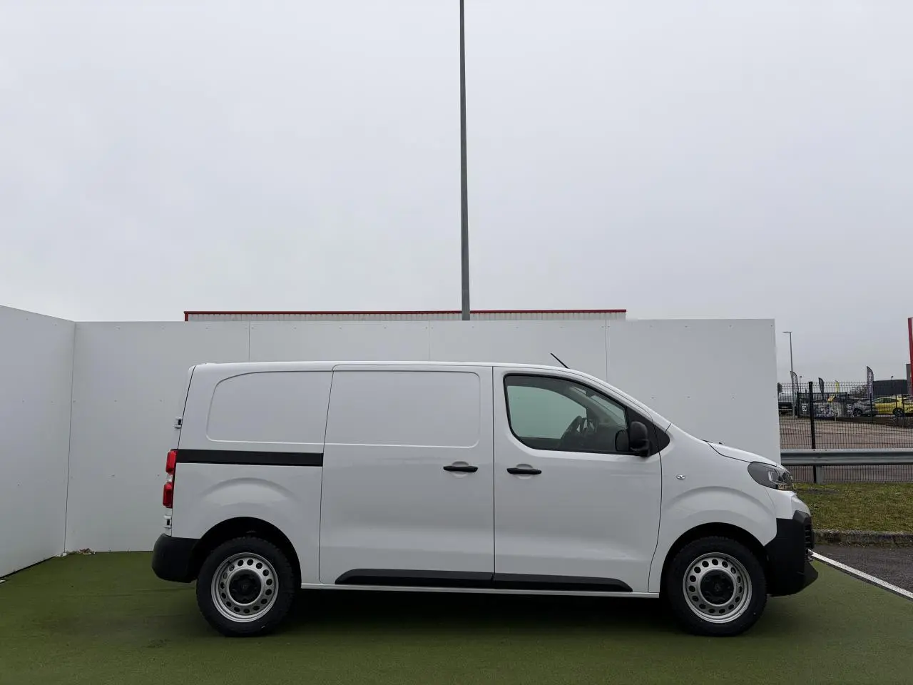 Vue de profil côté gauche d'un Peugeot Expert Fourgon blanc Icy avec jantes tôle 17 pouces et bande noire latérale.