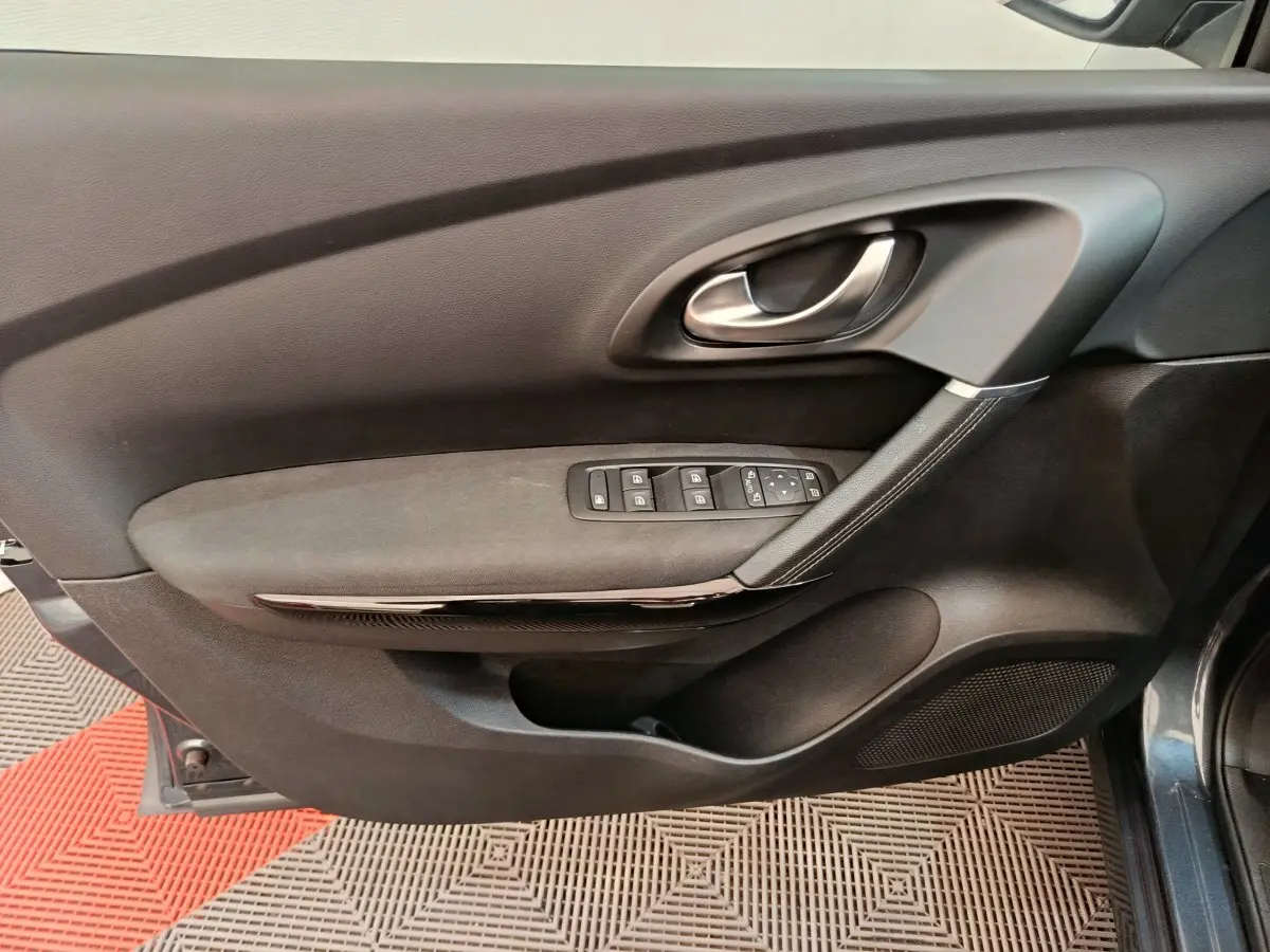 Vue intérieure de la porte avant gauche du Renault Kadjar gris foncé, avec commandes électriques et poignée argentée.