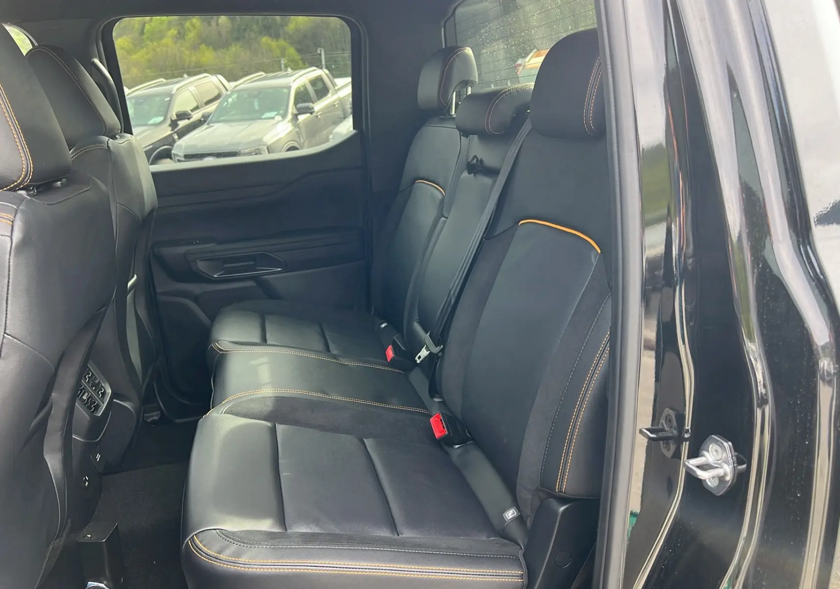 Vue intérieure côté droit sur la banquette arrière en cuir noir avec surpiqûres orange du Ford Ranger Wildtrak X 2025.