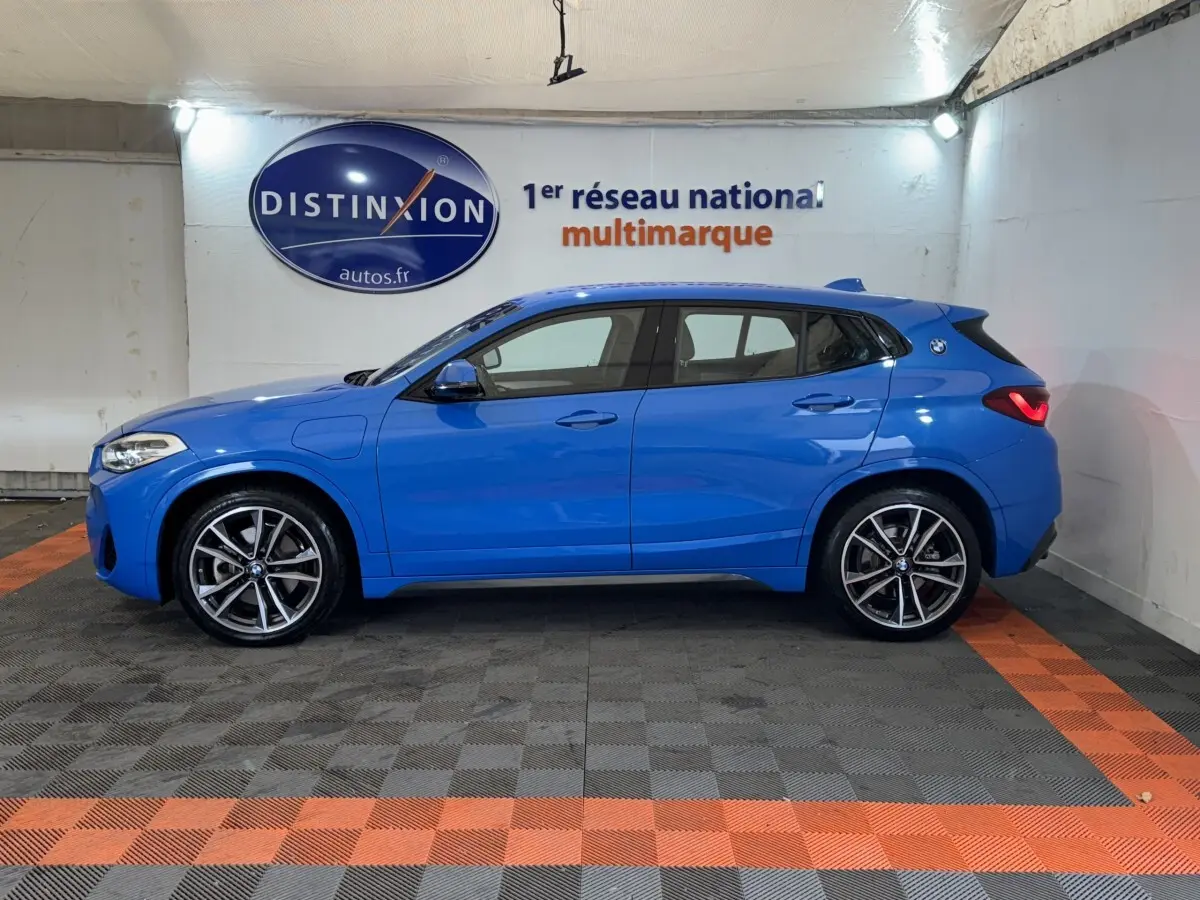 BMW X2 xDrive25e M Sport bleu, vue de profil côté gauche, avec jantes alliage et logo BMW sur l'aile arrière.
