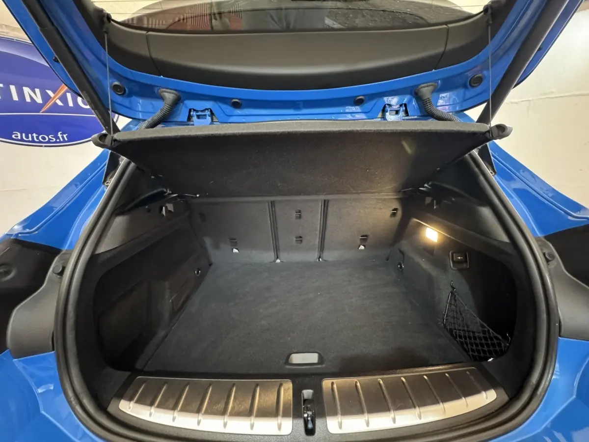 Coffre ouvert vu de l'arrière d'un BMW X2 xDrive25e M Sport bleu, avec protection seuil en aluminium visible.