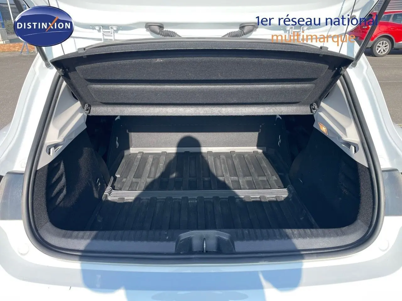 Coffre ouvert vu de l'arrière d'une Renault Clio Société blanc glacier, montrant l'espace de chargement vide et sa protection.