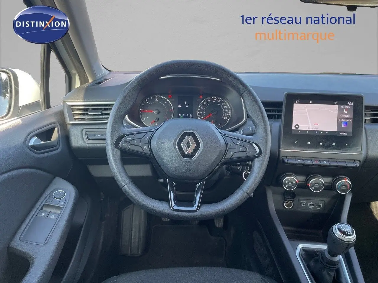 Vue intérieure centrée sur le volant Renault avec tableau de bord, écran tactile et levier de vitesse manuel.