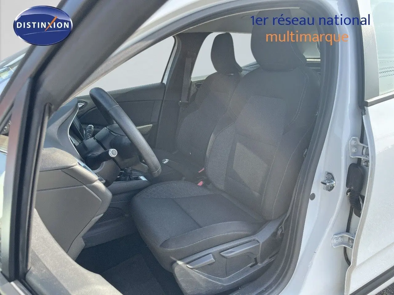 Intérieur côté conducteur d'une Renault Clio Société blanc glacier, sièges tissu gris noir et volant multifonction.