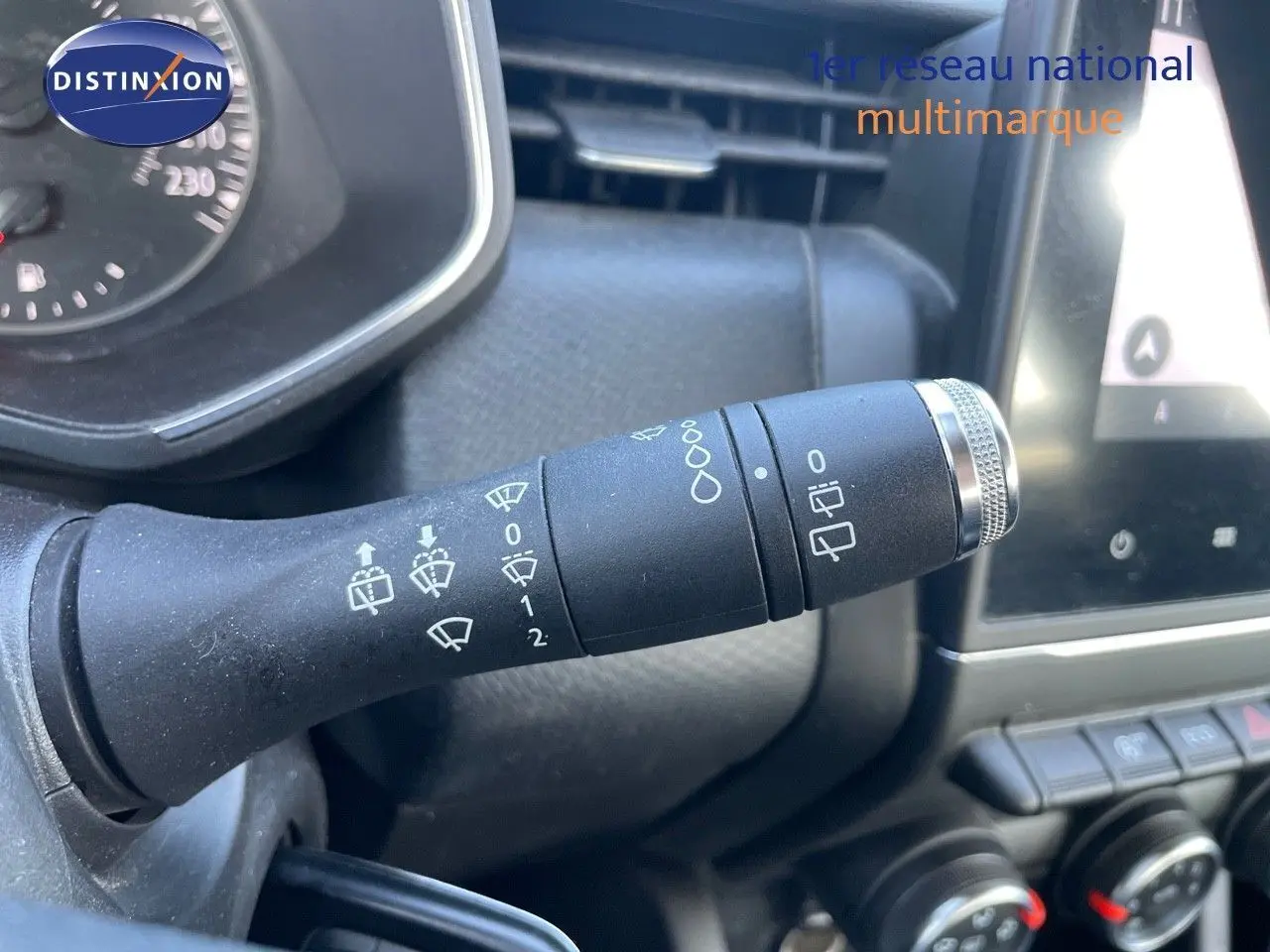 Gros plan sur la commande d'essuie-glace à gauche du volant du Renault Clio Société blanc glacier, tableau de bord en arrière-plan.