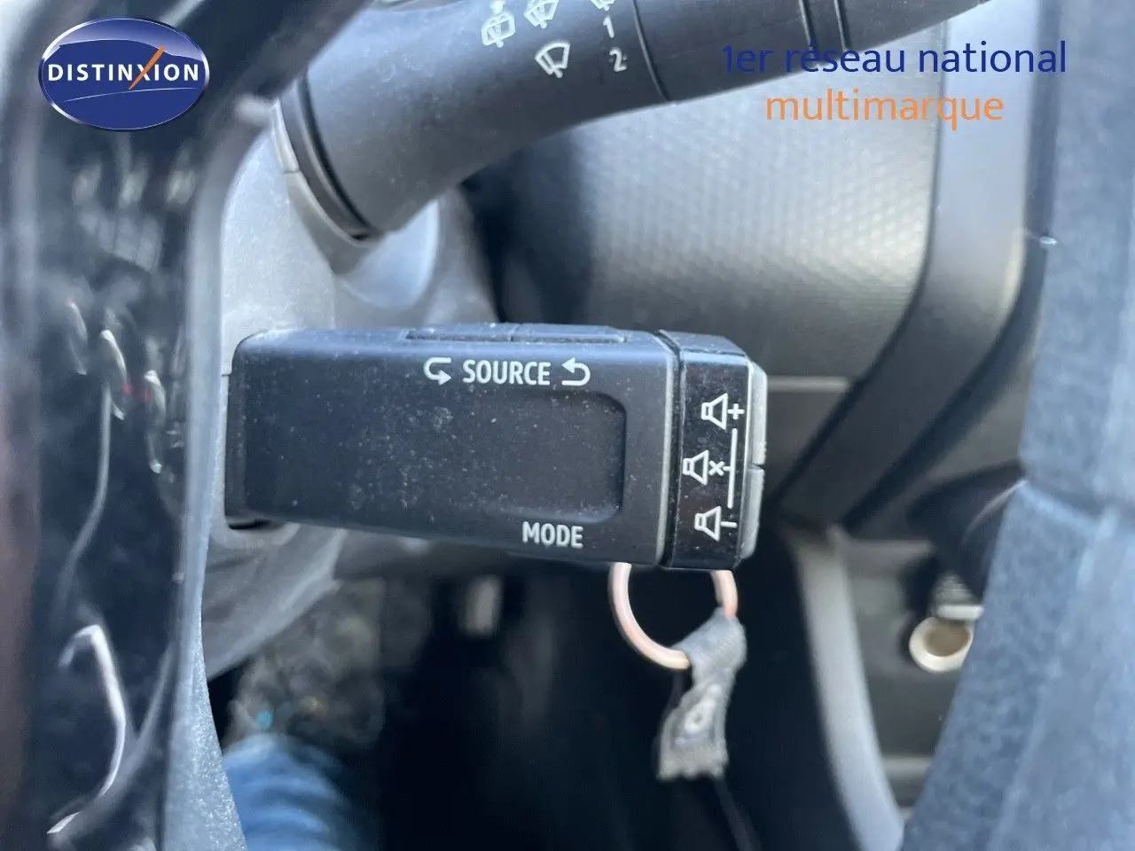 Gros plan sur la commande au volant noir de la Renault Clio Société blanche, mettant en valeur les réglages audio.